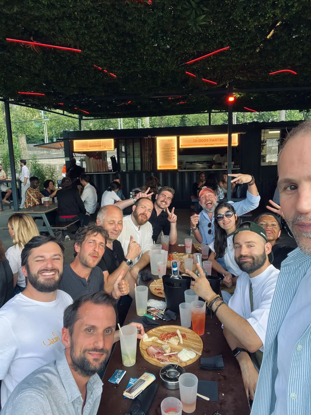 Selfie de l’équipe Happy-Zone attablée sous une pergola, lors de la garden party annuelle