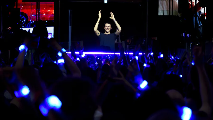 Artiste bras levés face à une foule aux bracelets LED bleus