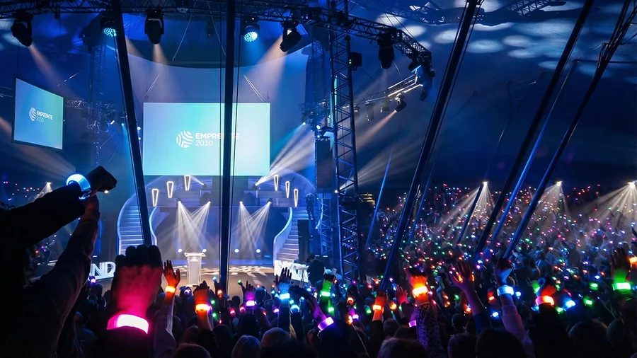 Bracelets LED allumés levés face à la scène d’une convention