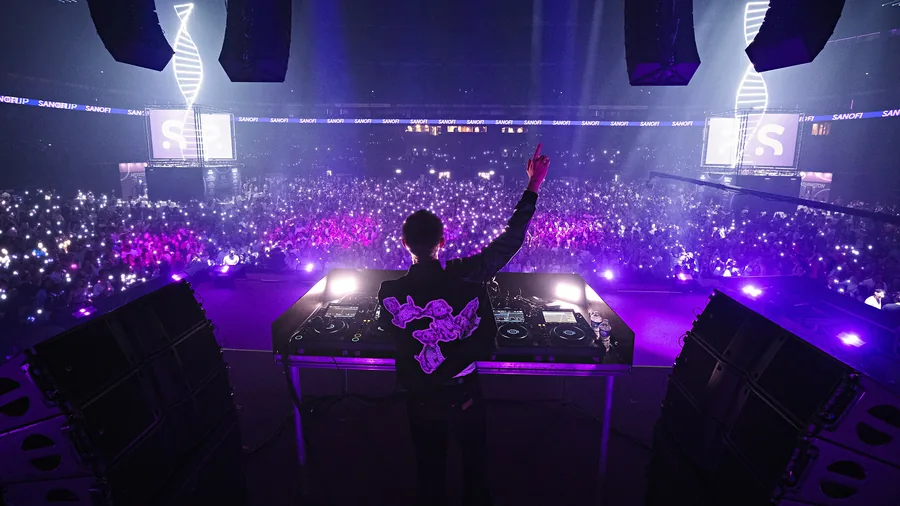 DJ face au public sous des lumières violettes, entre deux structures lumineuses