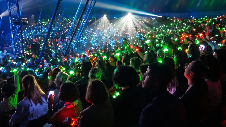 Foule dense aux bracelets LED verts et rouges sous des faisceaux lumineux