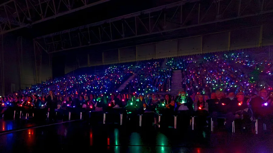 Grande salle remplie de spectateurs aux bracelets LED allumés