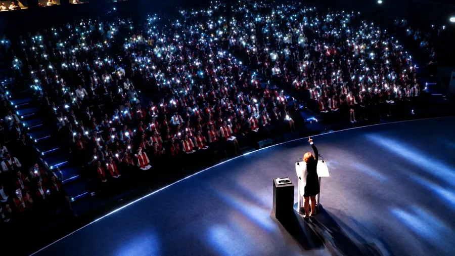Intervenante sur scène face à une salle illuminée par les bracelets LED
