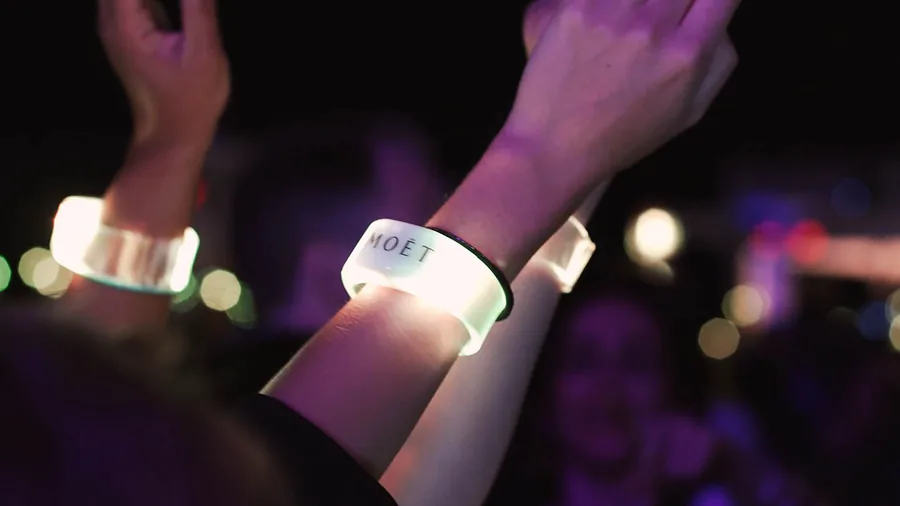 Poignets levés portant des bracelets LED lumineux lors d’une soirée