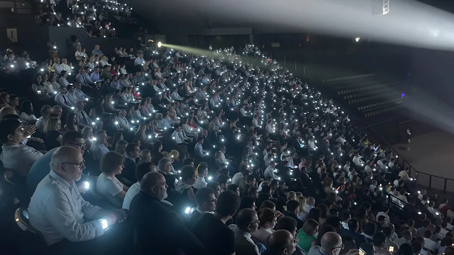 Public assis dans une salle, éclairé par des bracelets et lampes blanches