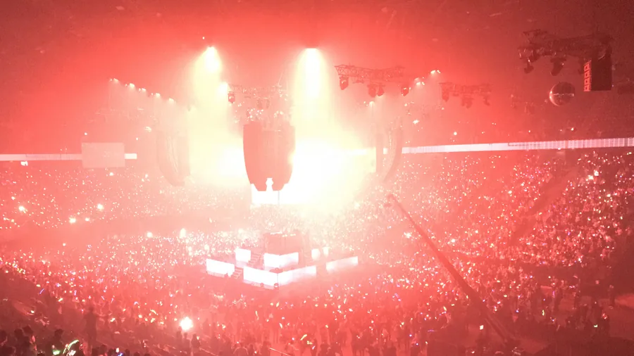 Grande salle baignée de lumière rouge, public équipé de bracelets LED